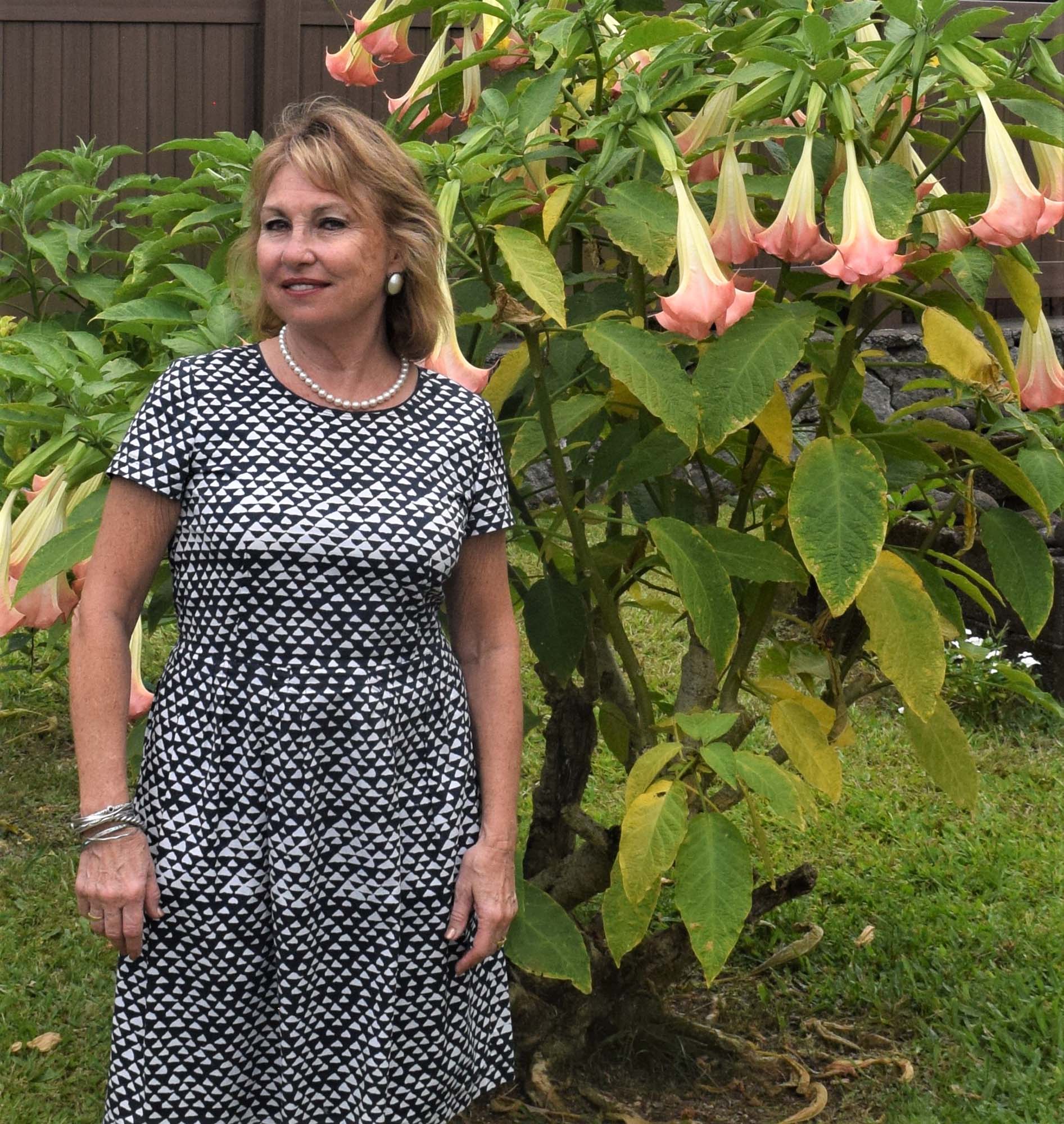 Kathleen Kentish Lucero standing beside flowering plants